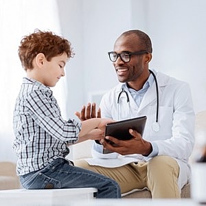 Doctor interacting with young patient using tablet.