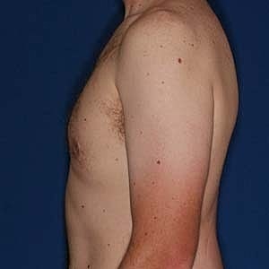 Side profile of a shirtless man against blue background.