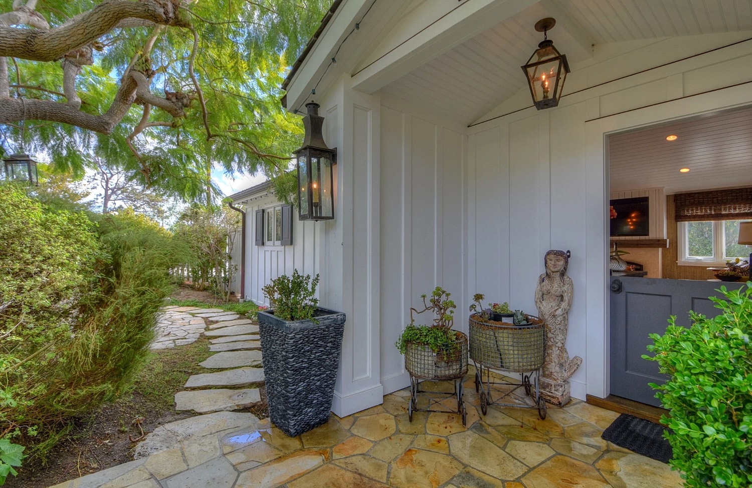 Charming entrance with plants and stone walkway.