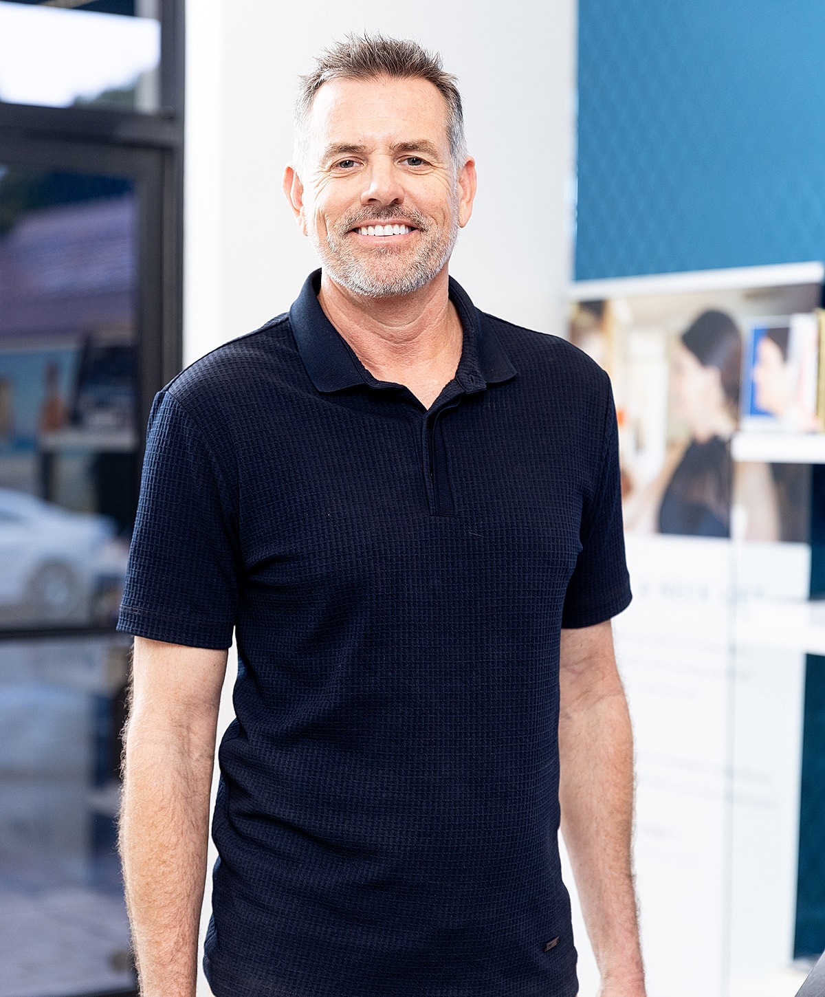 Smiling man in a black polo shirt.