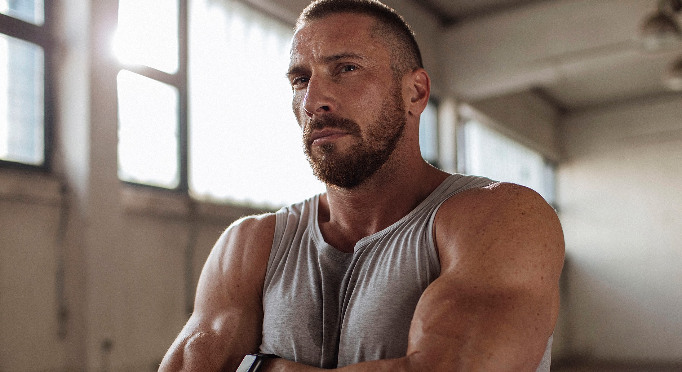 Muscular man in sleeveless shirt, serious expression.